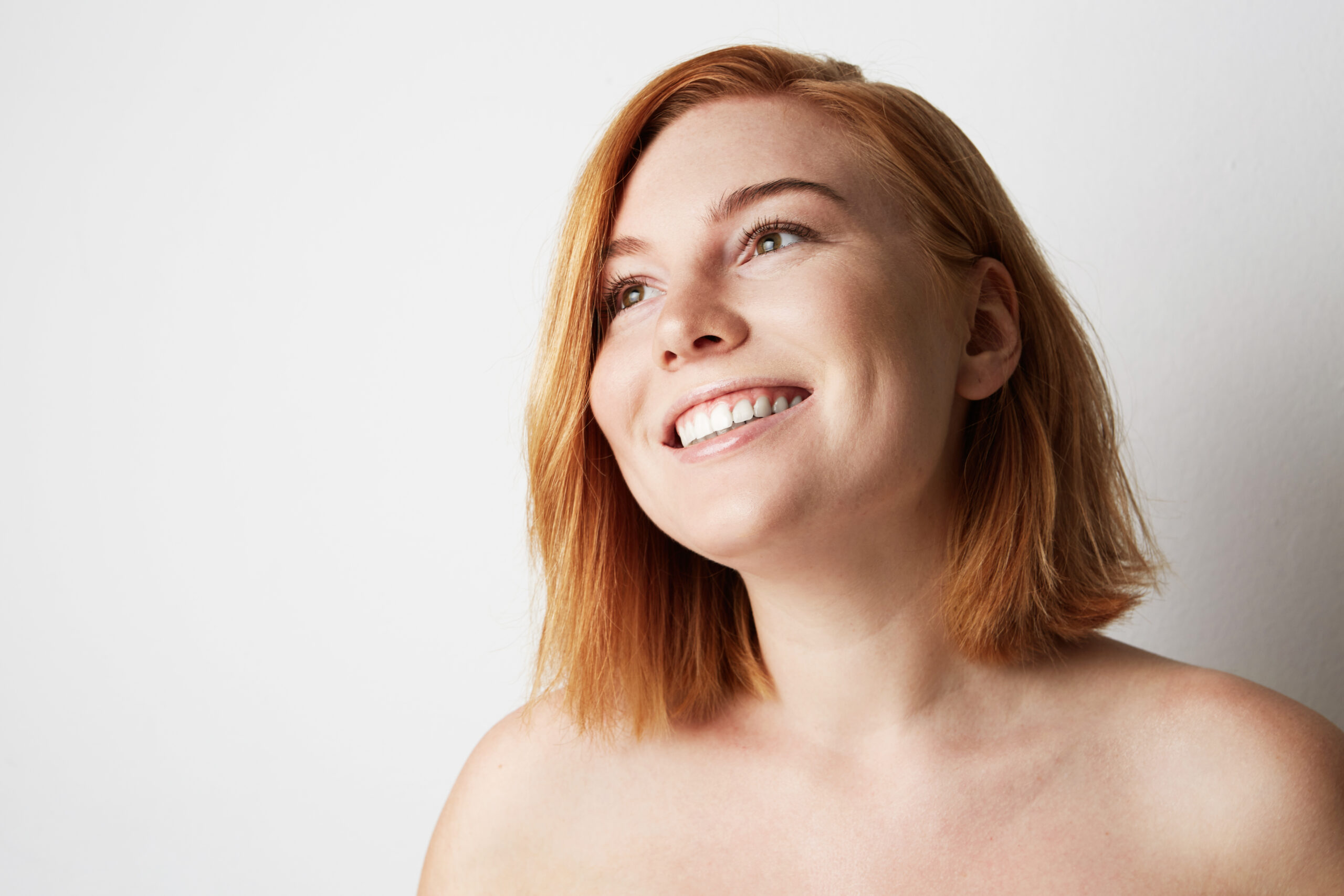 Happy young woman with natural make-up over white background. Close-up portrait.