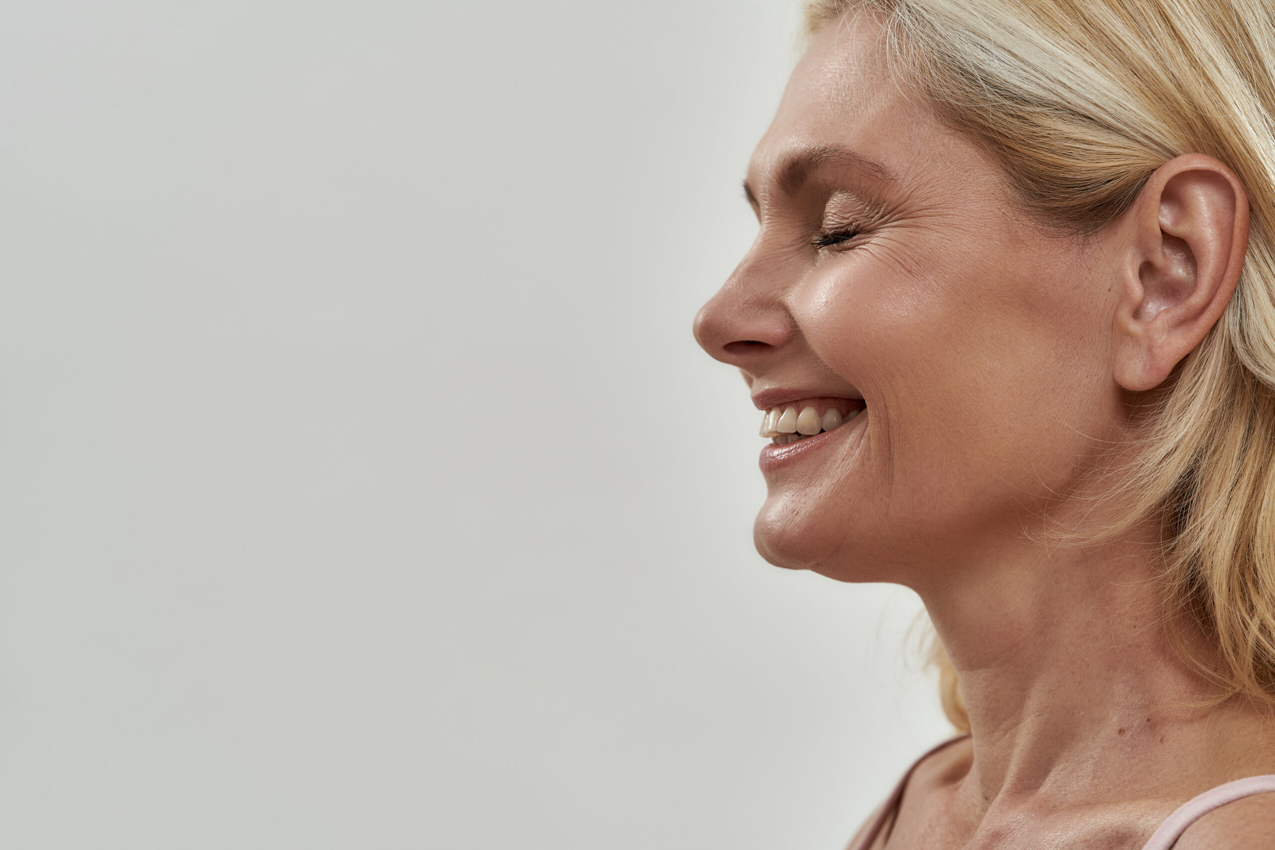 Happy middle aged woman laughing with closed eyes